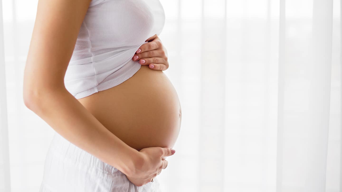 Pregnant woman standing next to window